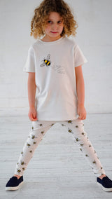Girl wearing white unisex organic cotton kid's T hirt and joggers with bee animal print