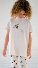 Girl wearing white unisex organic cotton kid's sweatshirt and joggers with bee animal print