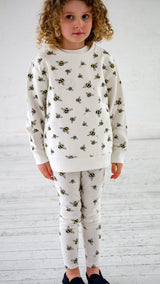 Girl wearing white unisex organic cotton kid's sweatshirt and joggers with bee animal print