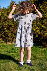 Girl wearing white organic cotton kid's dress with elephant animal print