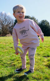 Blond boy wearing pink unisex organic cotton kid's sweatshirt with leopard animal print