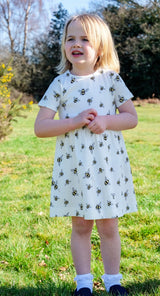 Girl wearing white unisex organic cotton dress with bee animal print outdoors