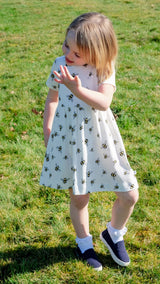 Girl wearing white unisex organic cotton dress with bee animal print