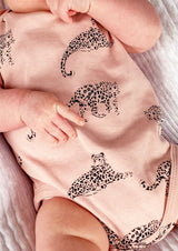 Close up of salmon pink organic cotton baby bodysuit with leopard animal print