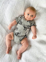 baby wearing grey organic cotton sleepsuit onesie with elephant animal print