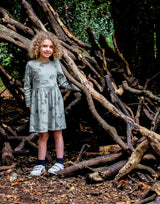 girl wearing organic cotton olive green girls dress with crocodile pattern
