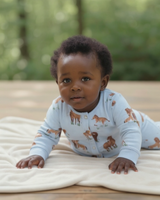 Baby crawling on a cream blanket, wearing a soft blue Exmoor pony print romper made from organic cotton