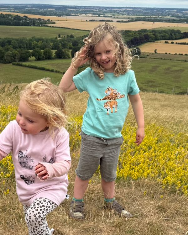 Two children standing in a field with a scenic landscape in the background